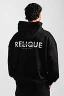 Person wearing a black hoodie with 'Relique' branding on the back against a white background