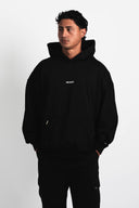 Person wearing a black hoodie with a brand logo on a white background